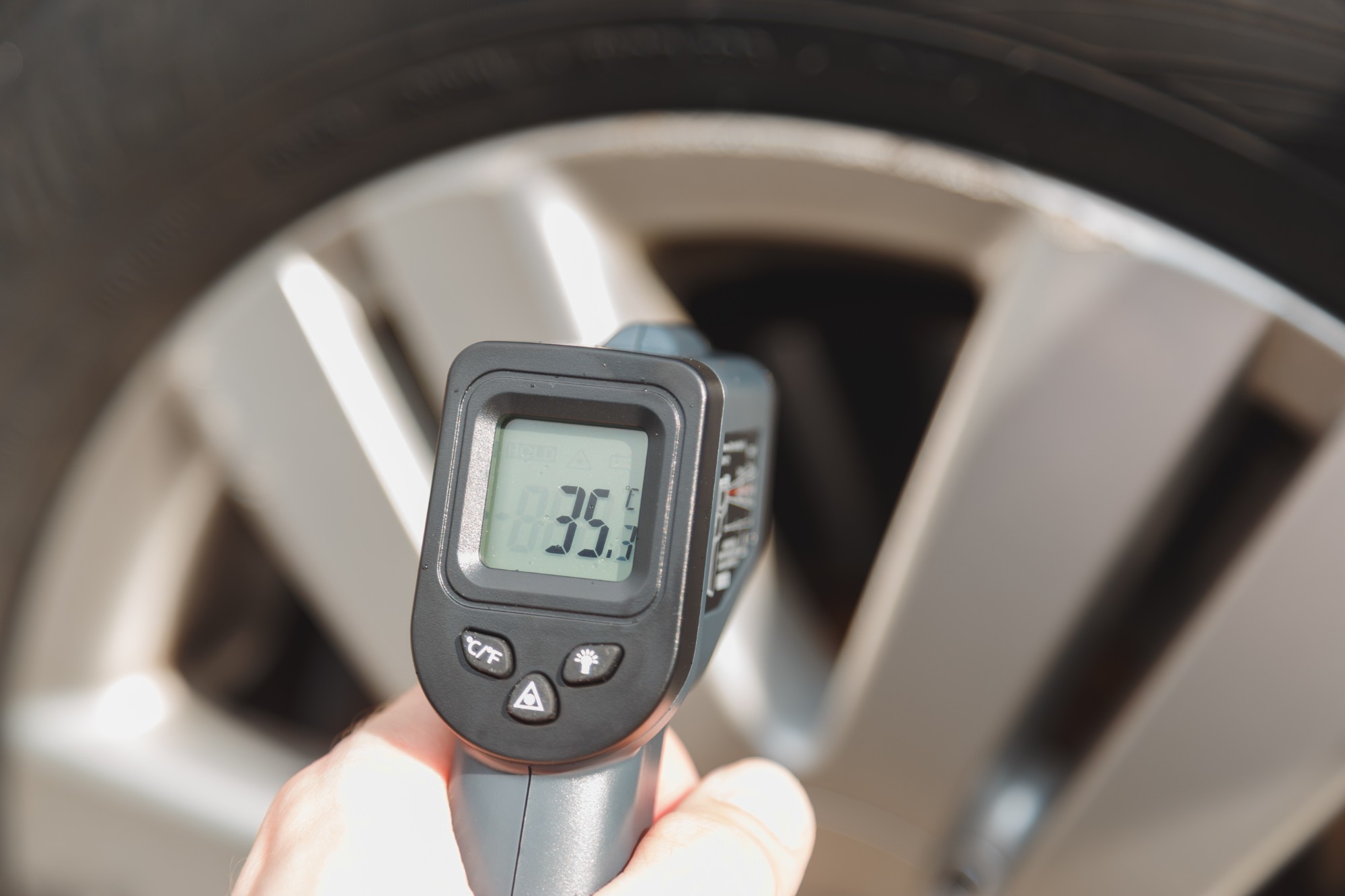 タイヤとホイールの温度を赤外線温度計で点検している自動車整備の様子